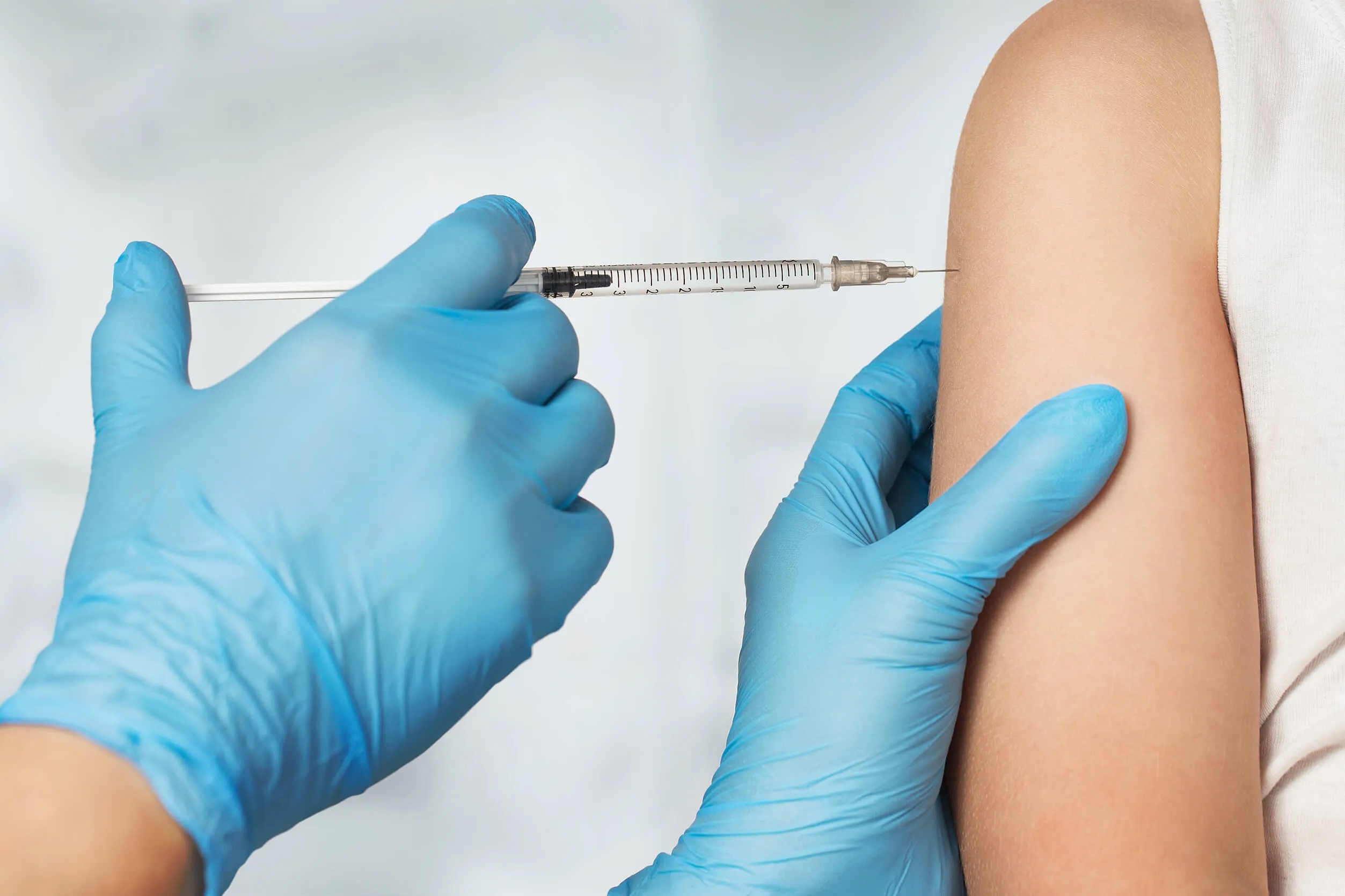Clinician administering an injection into a patient’s upper arm