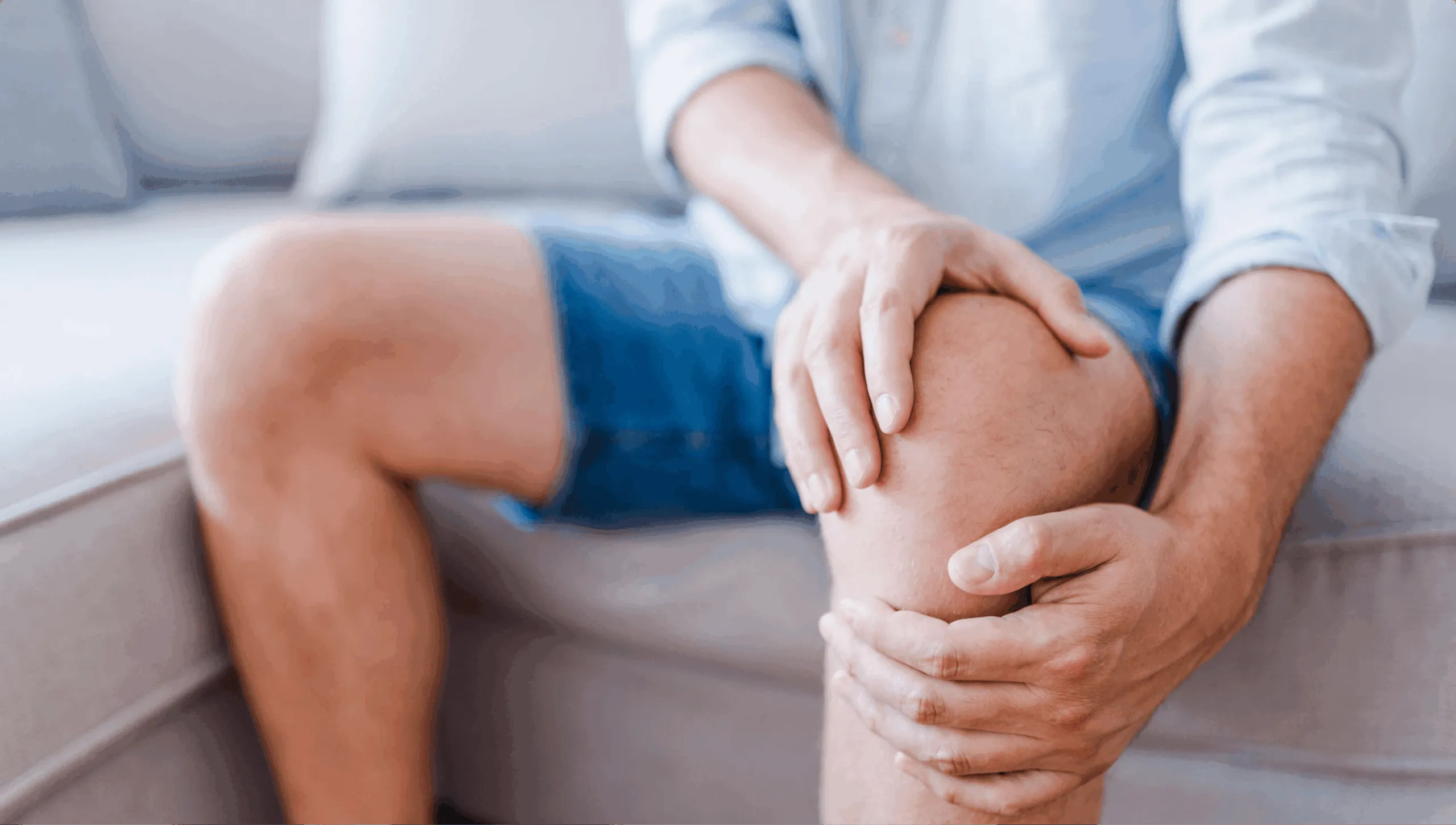 Person holding a painful knee while seated