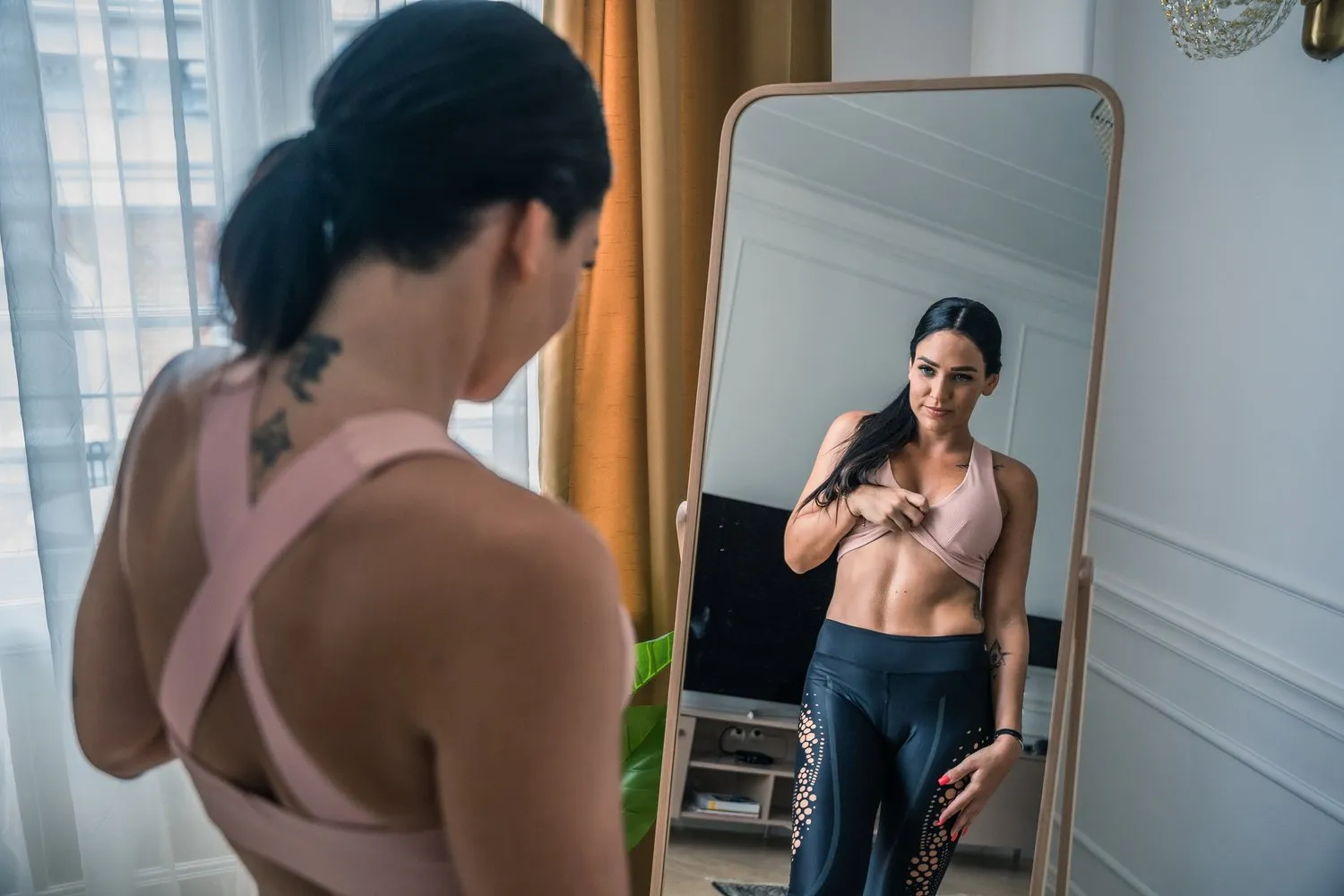 Woman looking at her reflection in a full-length mirror