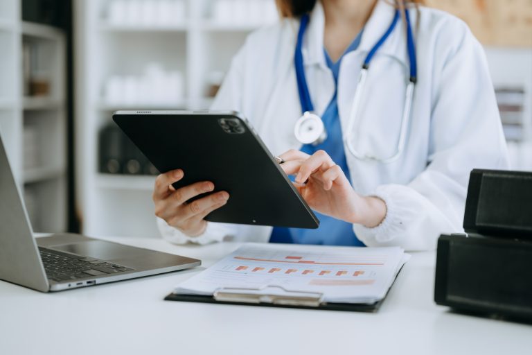 A doctor reviewing notes on a tablet at her desk