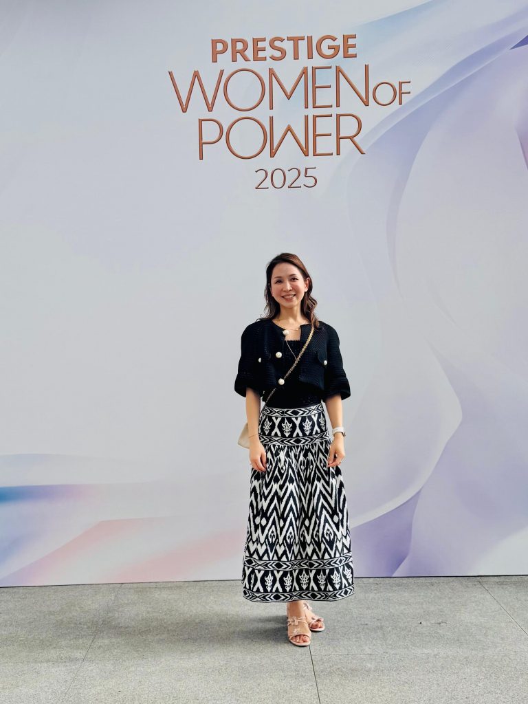 Woman standing before the Prestige Women of Power 2025 backdrop